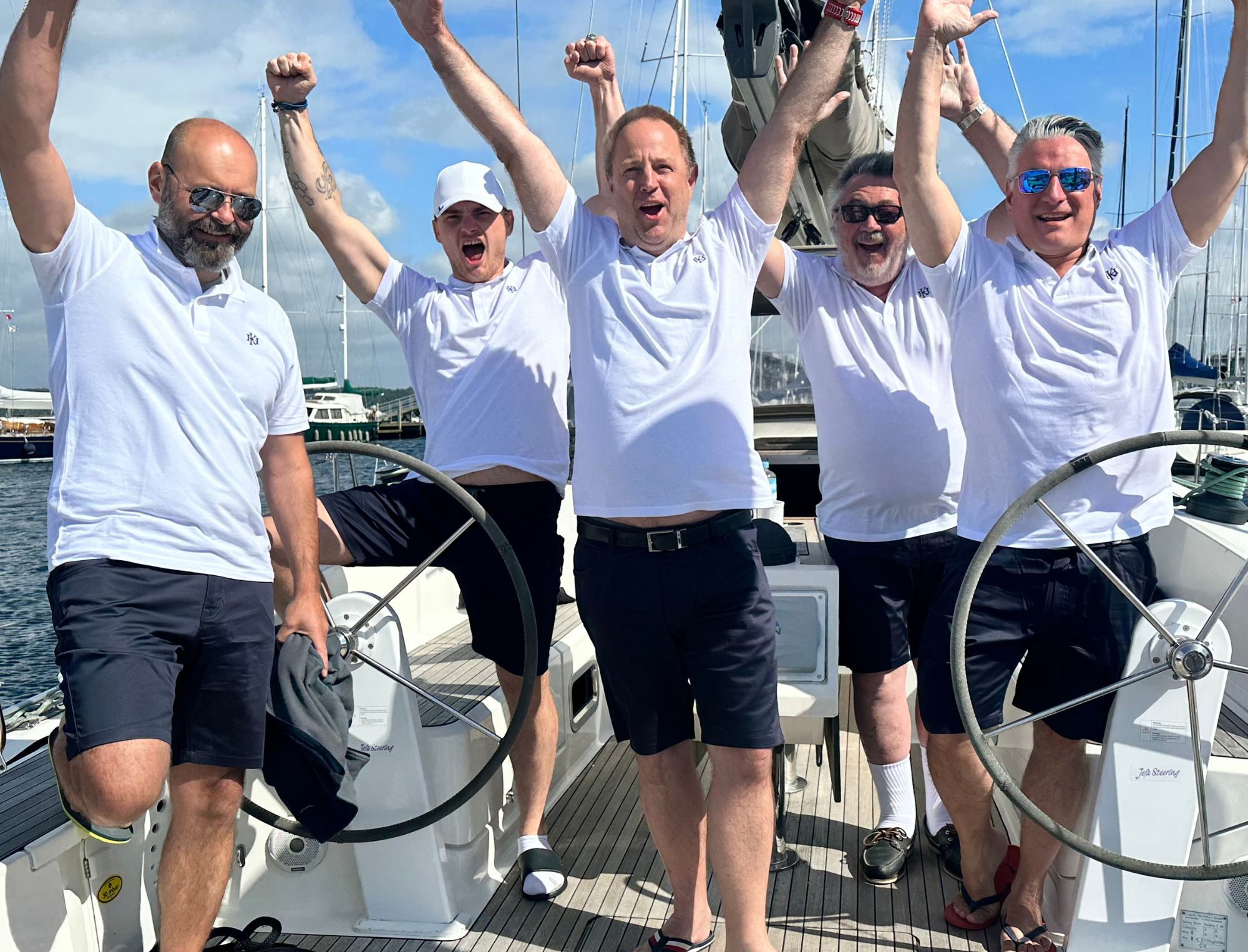 Ein Team von 5 Leuten stehen auf einem Boot und jubeln